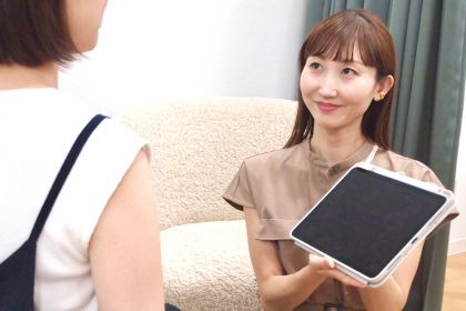 タブレットを見せながら治療について患者の女性に説明する医療スタッフ
